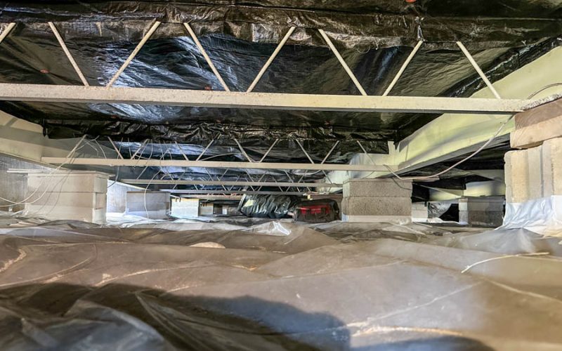 Completed mobile home crawl space encapsulation with black vapor barrier sealed across the under-home area